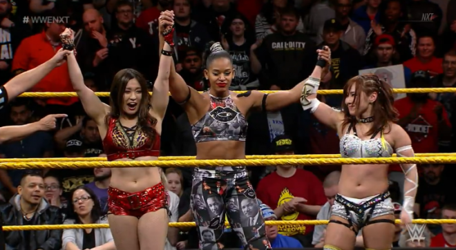 Shirai, Belair and Sane hold each other's arms high to celebrate their win on Feb 6, nXt.
