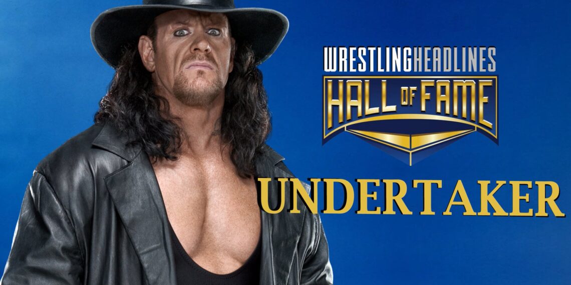 Undertaker stands with his trademark, wide-brimmed, black hat, shoulder length hair, open black leather jacket and black tank-top revealing most of his chest.